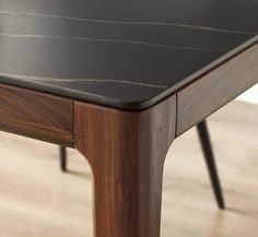 a wooden table with black marble top and two metal legs on the bottom, sitting on a hard wood floor