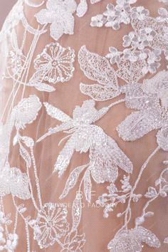 the back of a woman's wedding dress with white flowers and leaves on it