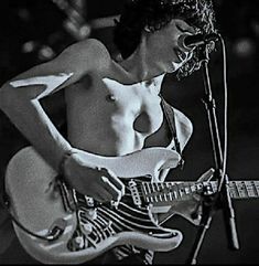 a naked woman playing an electric guitar in front of a microphone