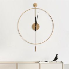 a clock mounted to the side of a white wall next to a table with a black bird on it