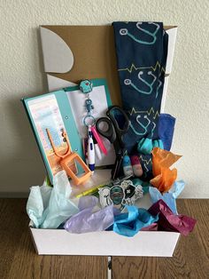 an open box with scissors and other crafting items in it on a wooden table