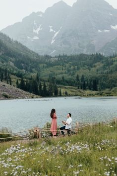 a man and woman standing next to each other near a lake