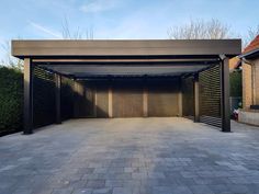 an empty garage with two doors open on the outside and brick walkway leading up to it