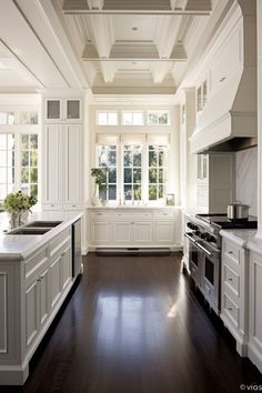 a large kitchen with white cabinets and wood flooring, along with an island in the middle