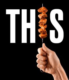 a hand holding a skewer of food with the word this spelled out in white