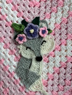 a crocheted blanket with flowers on it and a stuffed animal in the middle