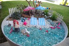 a potted planter filled with miniature beach toys and sand in the shape of a pool