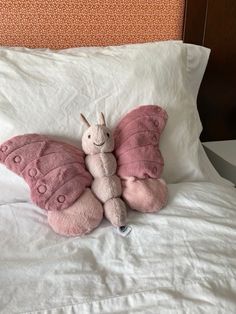 a pink butterfly stuffed animal laying on top of a bed