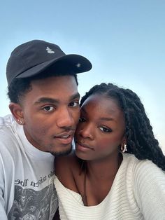 a man and woman are posing for a photo in front of the ocean with their heads close to each other