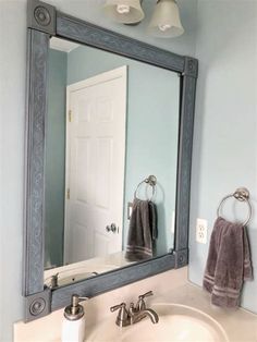 a bathroom sink sitting under a mirror next to a white door with two lights on it