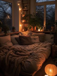 an unmade bed with lights on the windows and plants in the window sill