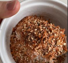 a person is holding a bowl full of food with seeds in it and sprinkled with seasoning