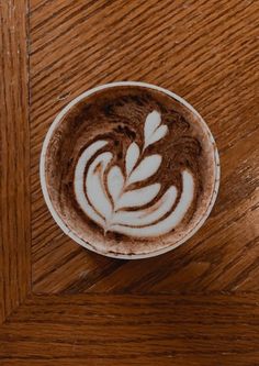 a cappuccino on a wooden table with white swirls in the foam