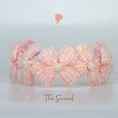 a pink headband with bows and pearls