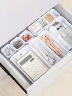 an organized drawer is shown with various items and utensils in the drawers, as well as a calculator