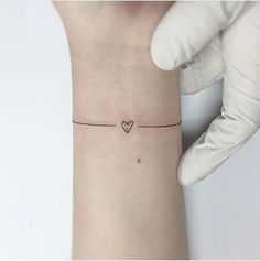 a woman's arm with a small heart tattoo on the left side of her wrist