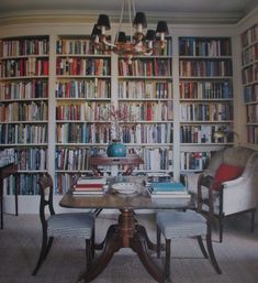 a dining room table surrounded by chairs and bookshelves filled with lots of books