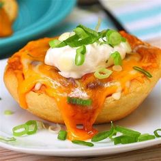 a piece of bread with cheese and green onions on it sitting on a white plate