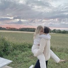 two people hugging each other in the middle of a field