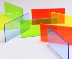 several different colored glass pieces on a white surface with one in the middle and one in the back