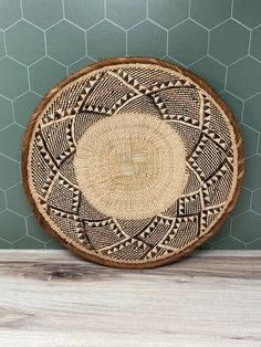 a woven basket sitting on top of a wooden table next to a green tiled wall