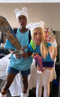 two people in costumes standing next to each other near a bed and holding an object