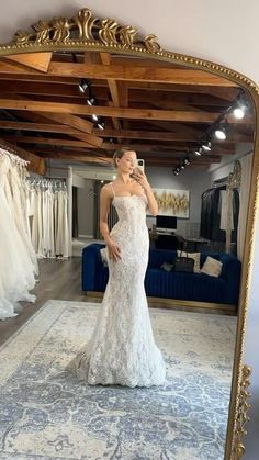 a woman taking a selfie in front of a mirror with her wedding dress on display