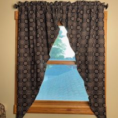 an open window with black and white curtains in front of the window is a view of a swimming pool