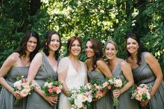 a group of women standing next to each other in front of trees and greenery