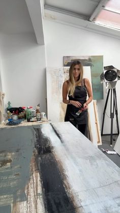 a woman standing in front of an easel with paint on it and another painting behind her