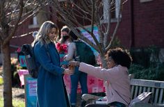 two women shaking hands on a park bench