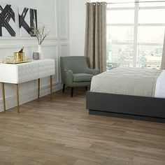 a bedroom with white walls and wood floors, two chairs, an end table and a bed