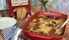 a red casserole dish sitting on top of a wooden table next to a package of panettone