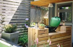 a green container sitting on top of a wooden box next to a planter filled with flowers