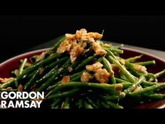 a red plate topped with green beans and walnuts