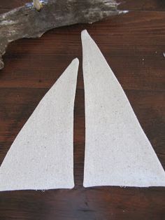 two white sailboats sitting on top of a wooden table next to a piece of driftwood