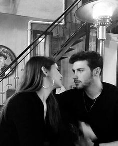 a man and woman sitting next to each other in front of a stair case at a restaurant