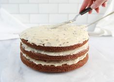 someone is cutting into a cake with white frosting