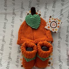 an orange knitted hat and pair of baby booties on top of a table