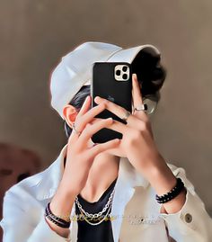 a woman taking a selfie with her cell phone while wearing a white coat and black bracelets