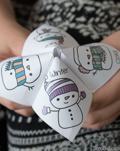 a person holding two paper snowmen in their hands