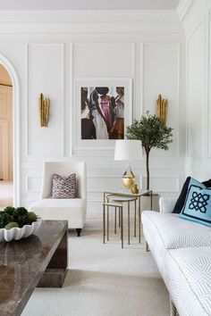 a living room filled with furniture and a painting on the wall above it's coffee table