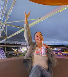 a woman sitting on top of a ferris wheel holding up her arms in the air