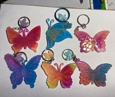 six different colored butterfly keychains sitting on top of a piece of paper