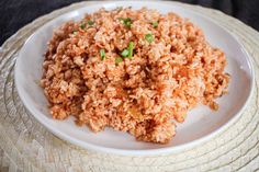 a white plate topped with rice and green onions