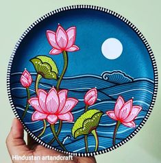 a hand holding up a plate with flowers painted on it