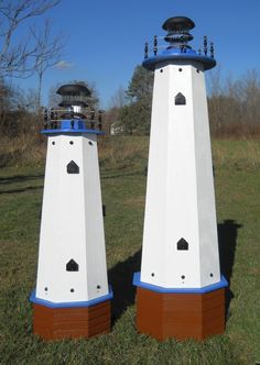 two white and blue lighthouses sitting in the grass