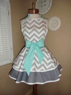 a woman's dress made out of gray and white chevrons with a green bow