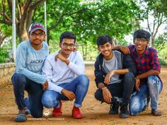 three young men are posing for the camera in front of trees and dirt ground with their arms around each other