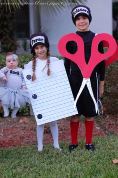 two children dressed up in costumes with paper scissors on their heads and one holding a sign